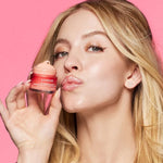 Woman with glossy lips holding Laneige Lip Sleeping Mask Berry against pink background