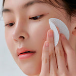 Woman using toner pad on face for skincare routine, close-up of glowing skin